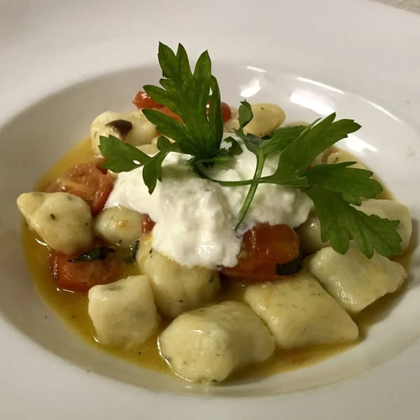 Clemente's Pizzeria & Cafe Italiano's gnocchi with cherry tomatoes, ricotta, and parsley in a white bowl.